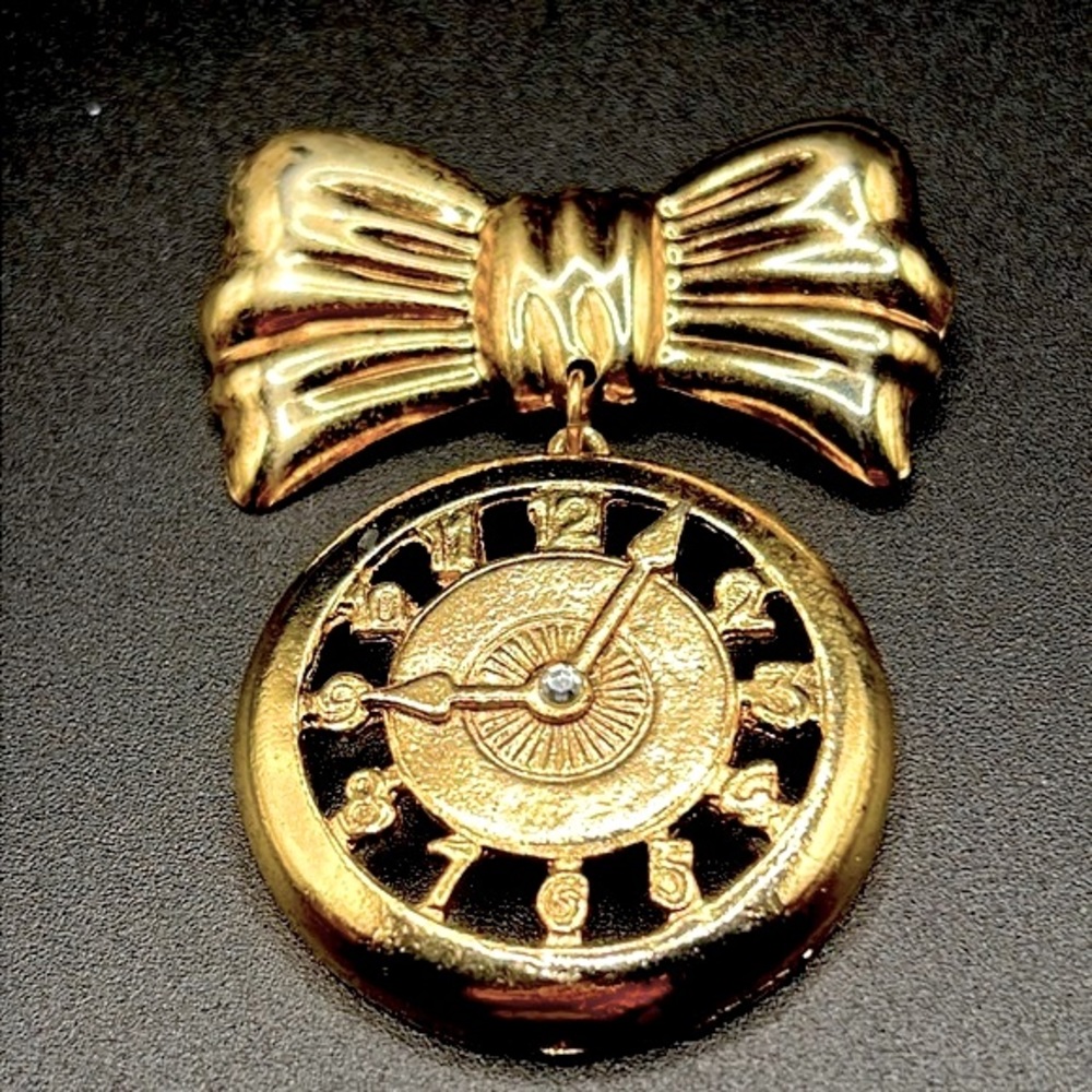 Gold tone faux clock brooch openwork with rhinestone center and gold tone bow …